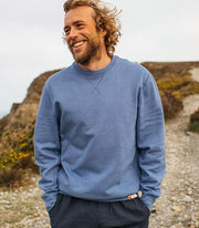 Man wears a classic cotton sweatshirt in blue. Made from durable and heavyweight loopback organic cotton.